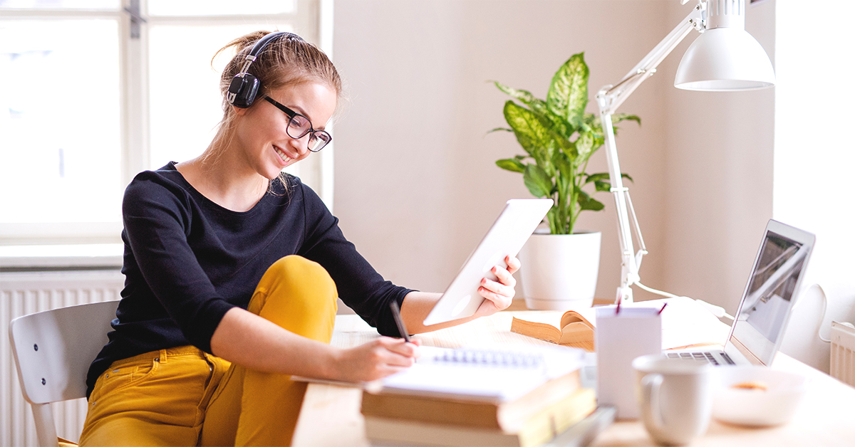 A woman with headphones on looking at a tablet