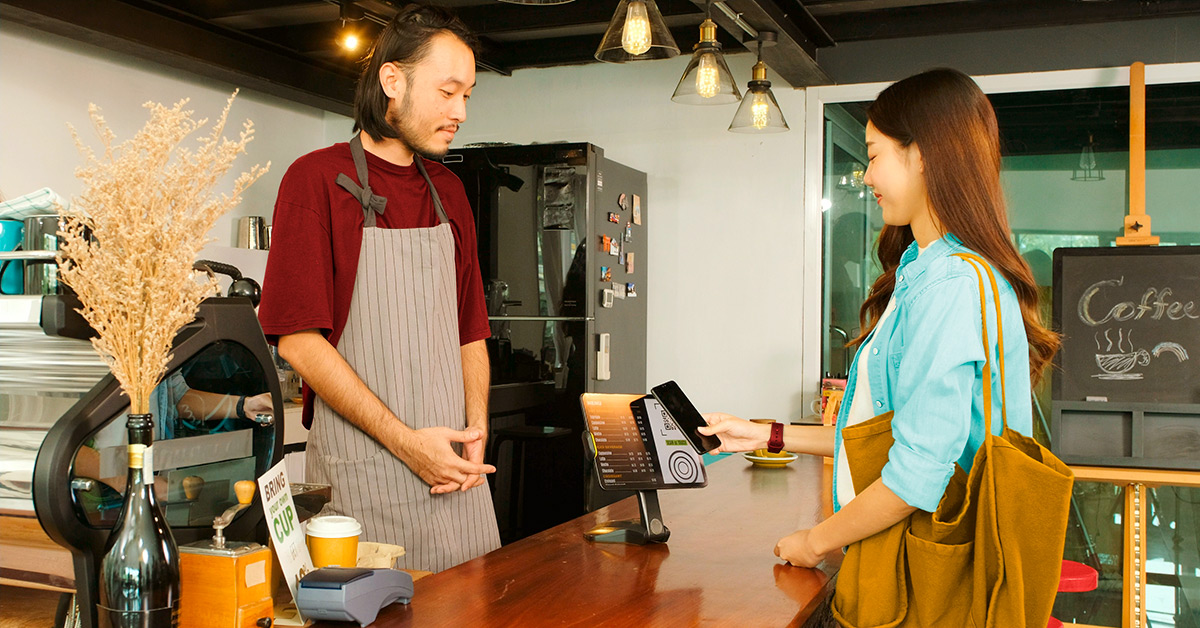 Worker in a restaurant accepting mobile payment from a customer