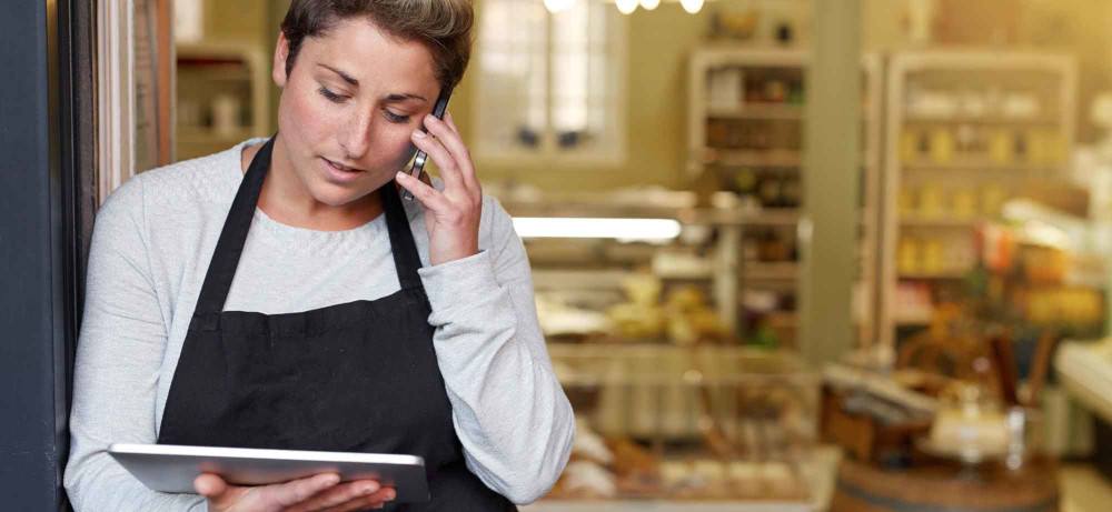 Woman in small business with tablet and phone