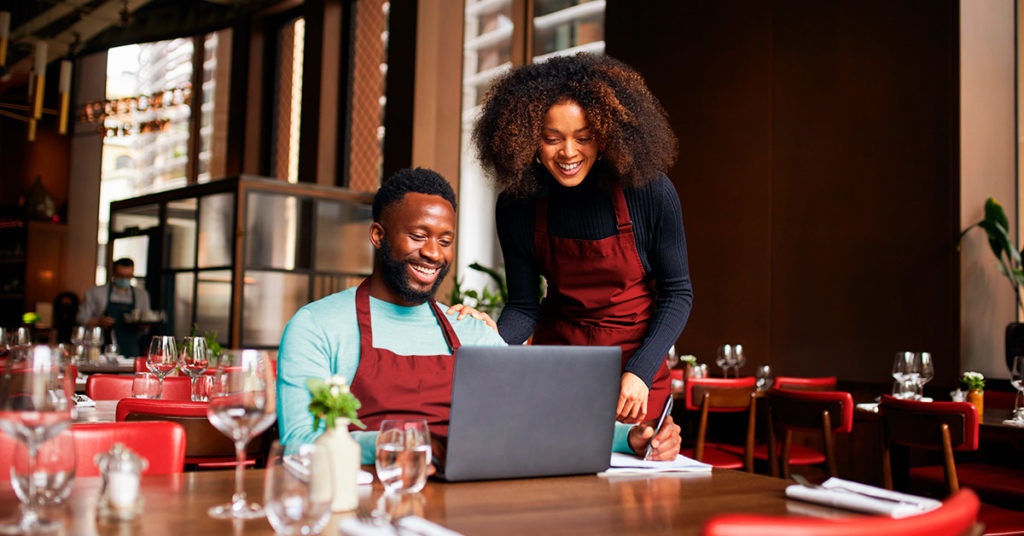 Two people in a restaurant looking at a computer