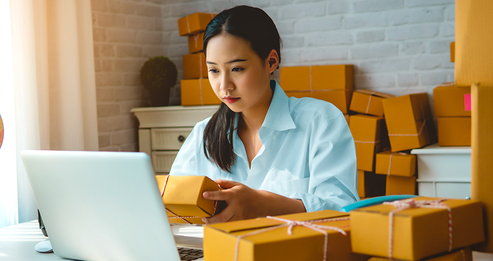 Woman at a computer preparing a package for shipment