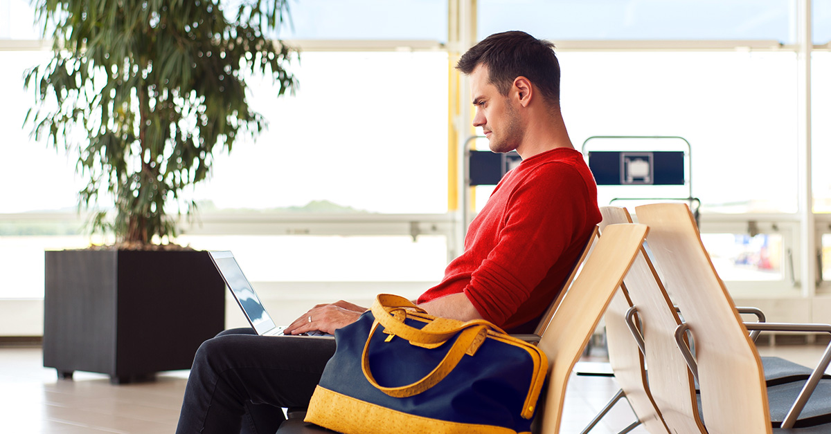 Man working on a laptop sitting at an airport