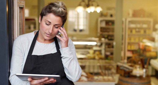 Woman in small business with tablet and phone