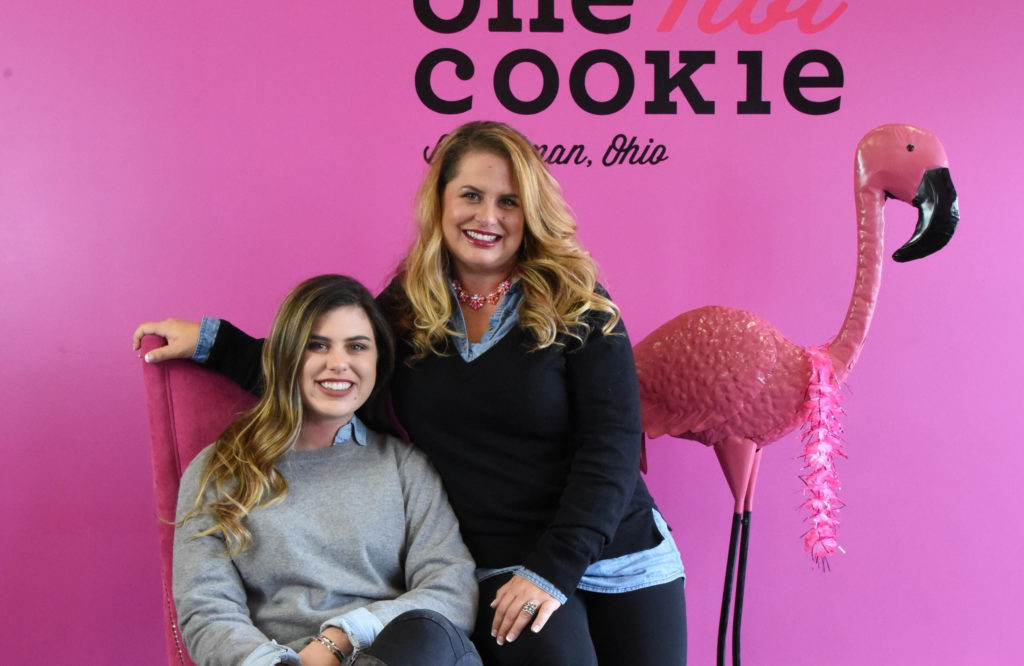 Two women next to each other against a pink wall