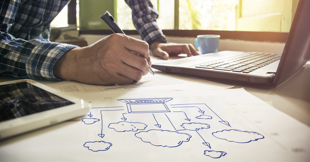 Person sitting at a computer sketching a cloud storage diagram