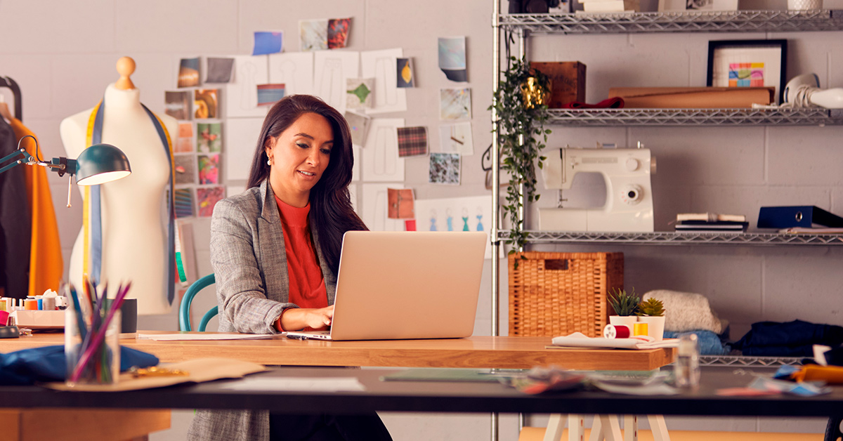 Fashion designer sitting at a table working on a computer