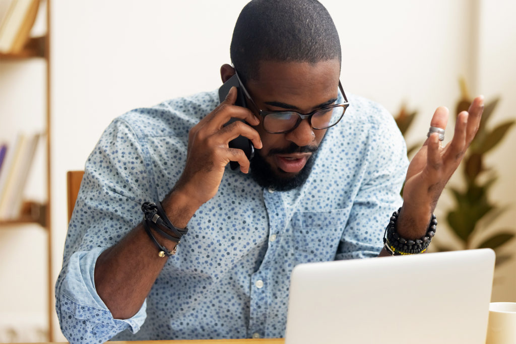 A man looking at a computer talking on a phone