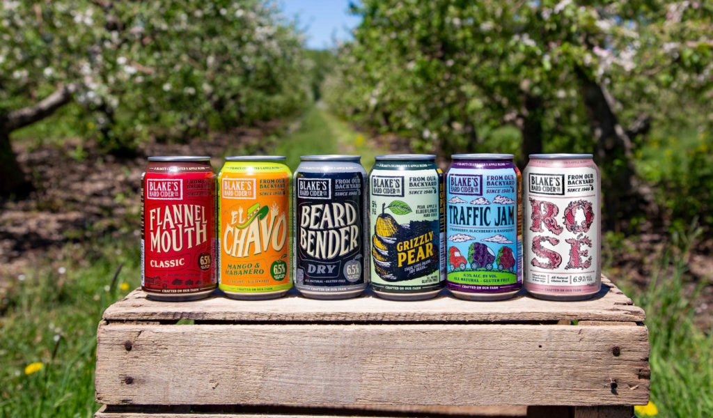 6 cans of cider placed next to each other outside on a farm