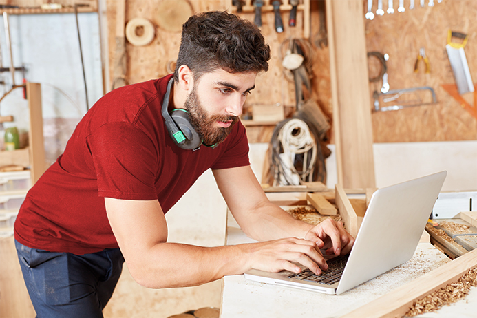 Carpenter in a workshop looking at a computer