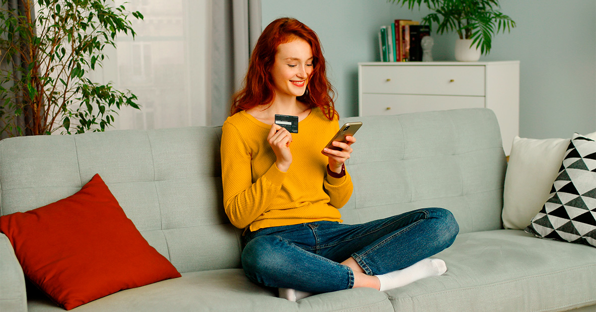 Woman sitting on a couch making an online purchase with her phone