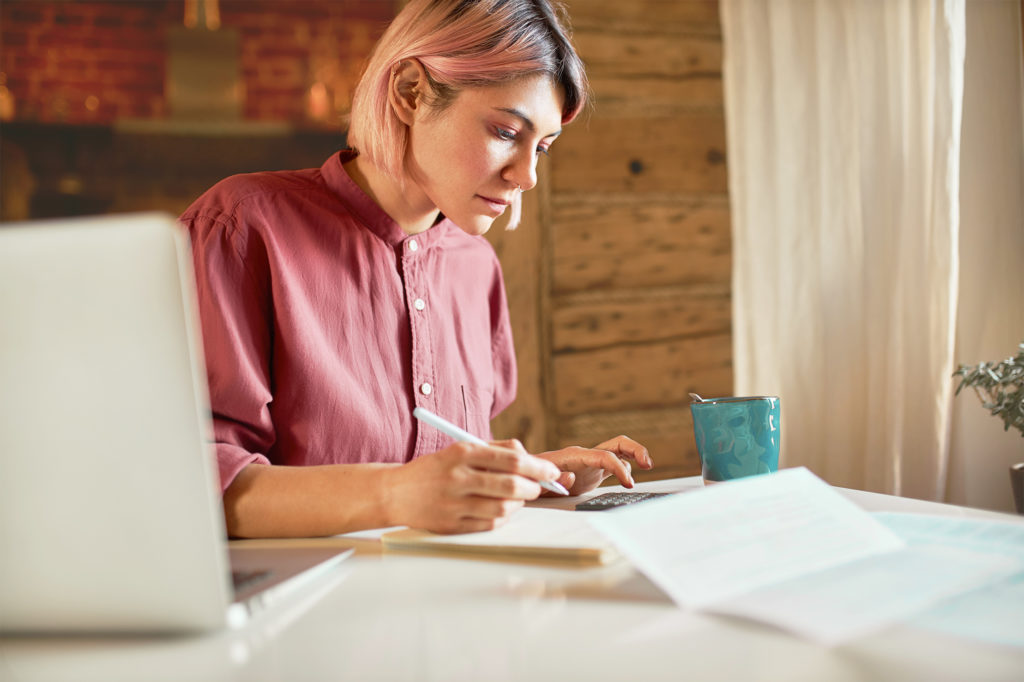 Woman sitting at a computer using a calculator