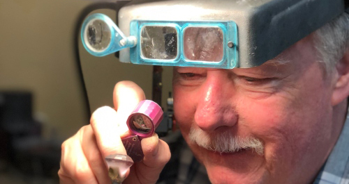 A jeweler looking through a magnify glass at a piece of jewelry