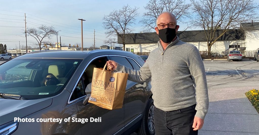 Man wearing a mask holding a to-go back