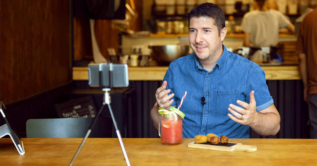 Person with a drink and food filming a podcast
