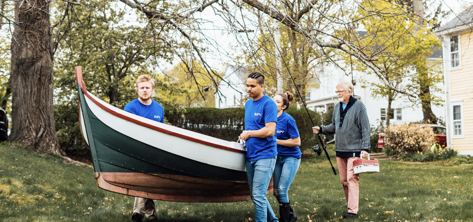 People helping carry a row boat