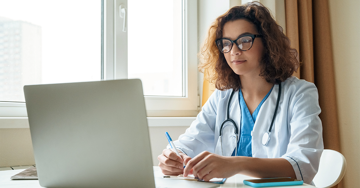 Doctor sitting at a desk looking at a computer