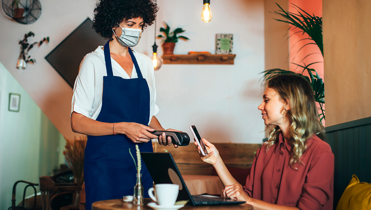 A worker in a restaurant taking someones payment from mobile phone