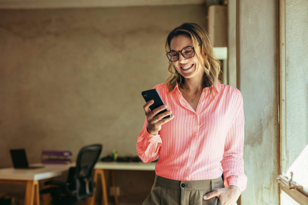 A woman smiling looking at her phone