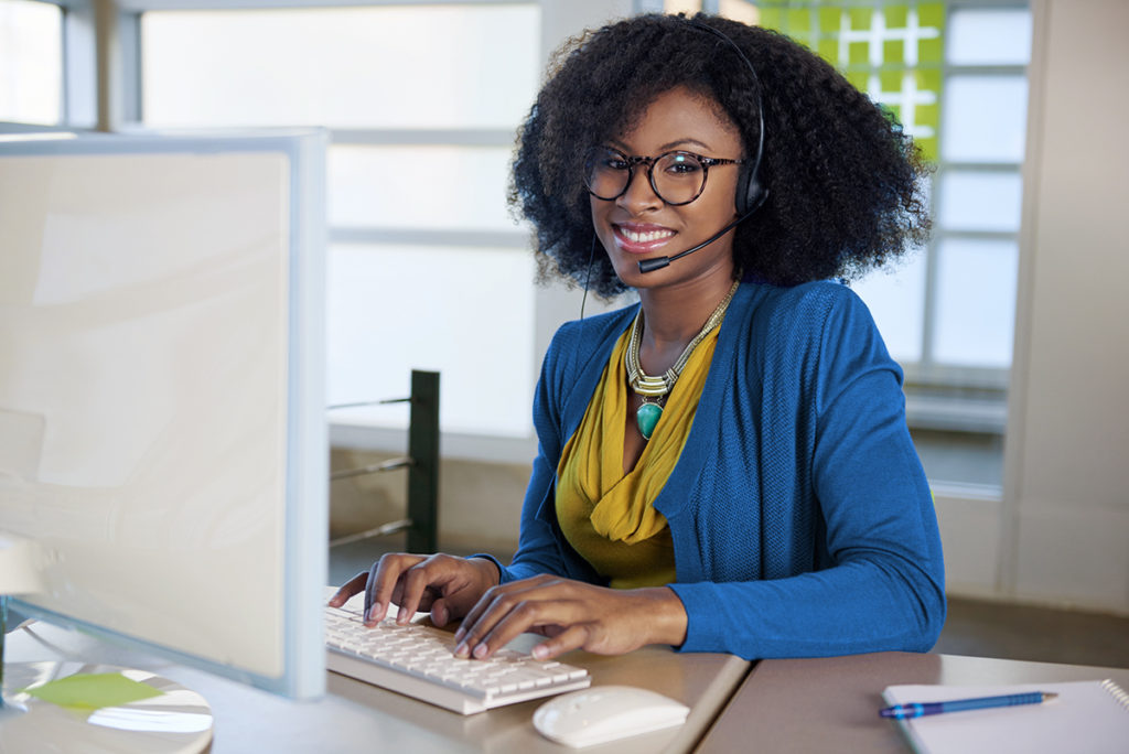 A woman wearing a headset working on a computer