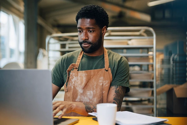 A man in a smock typing on a laptop with Frontier Internet Backup