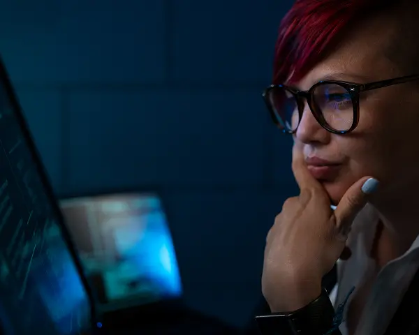 A woman in glasses looking at a laptop screen
